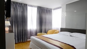 A hotel room with a large bed, a bedside table, a lamp, and a chair. - Hotel My World (Mandalay)