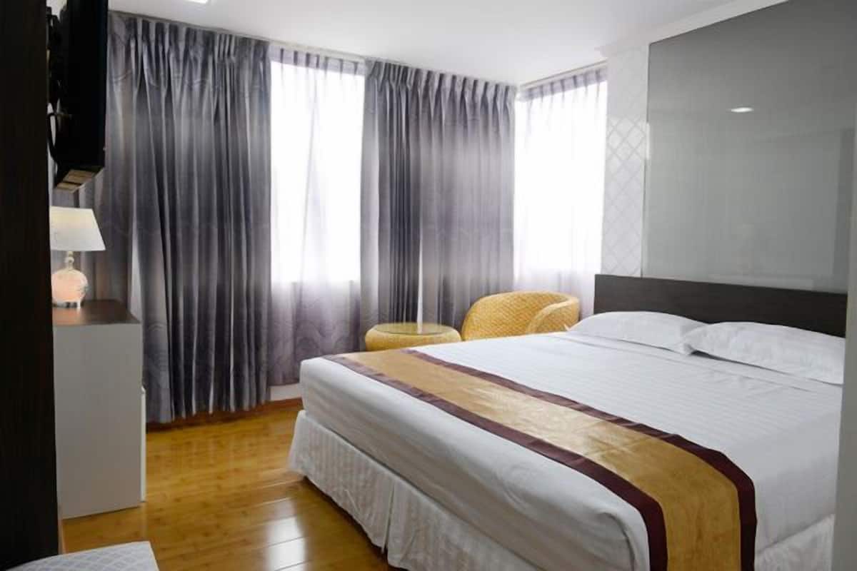 A hotel room with a large bed, a bedside table, a lamp, and a chair.