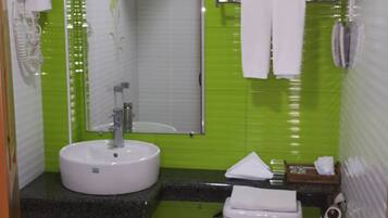 A small bathroom with a sink, mirror, toilet, and towel rack.