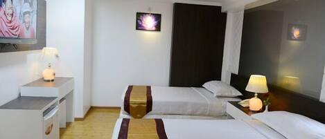 A hotel room with two beds, a desk, a TV, and a wall-mounted picture.