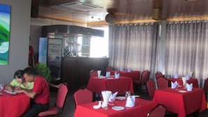 A restaurant with red tablecloths, white napkins, and chairs. There are people seated at tables. - Hotel My World (Mandalay)
