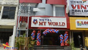 A hotel named "MY WORLD" with a red and white facade, balconies, and a sign for "LOOK OK" advertising sticker films. - Hotel My World (Mandalay)