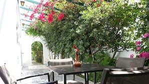 An outdoor seating area with a table and chairs, surrounded by lush greenery and flowering plants. - Karis Hotel (Kos)