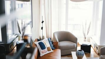 A modern living room with a sofa, armchairs, a coffee table, and a large window with curtains.
