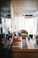 Uma sala de estar moderna com sofá, poltronas, mesa de centro e uma janela grande com cortinas.