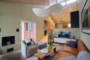 A modern living room with a sofa, armchair, coffee table, and a flat-screen TV. - Barsebäck Resort Hotell (Loddekopinge)
