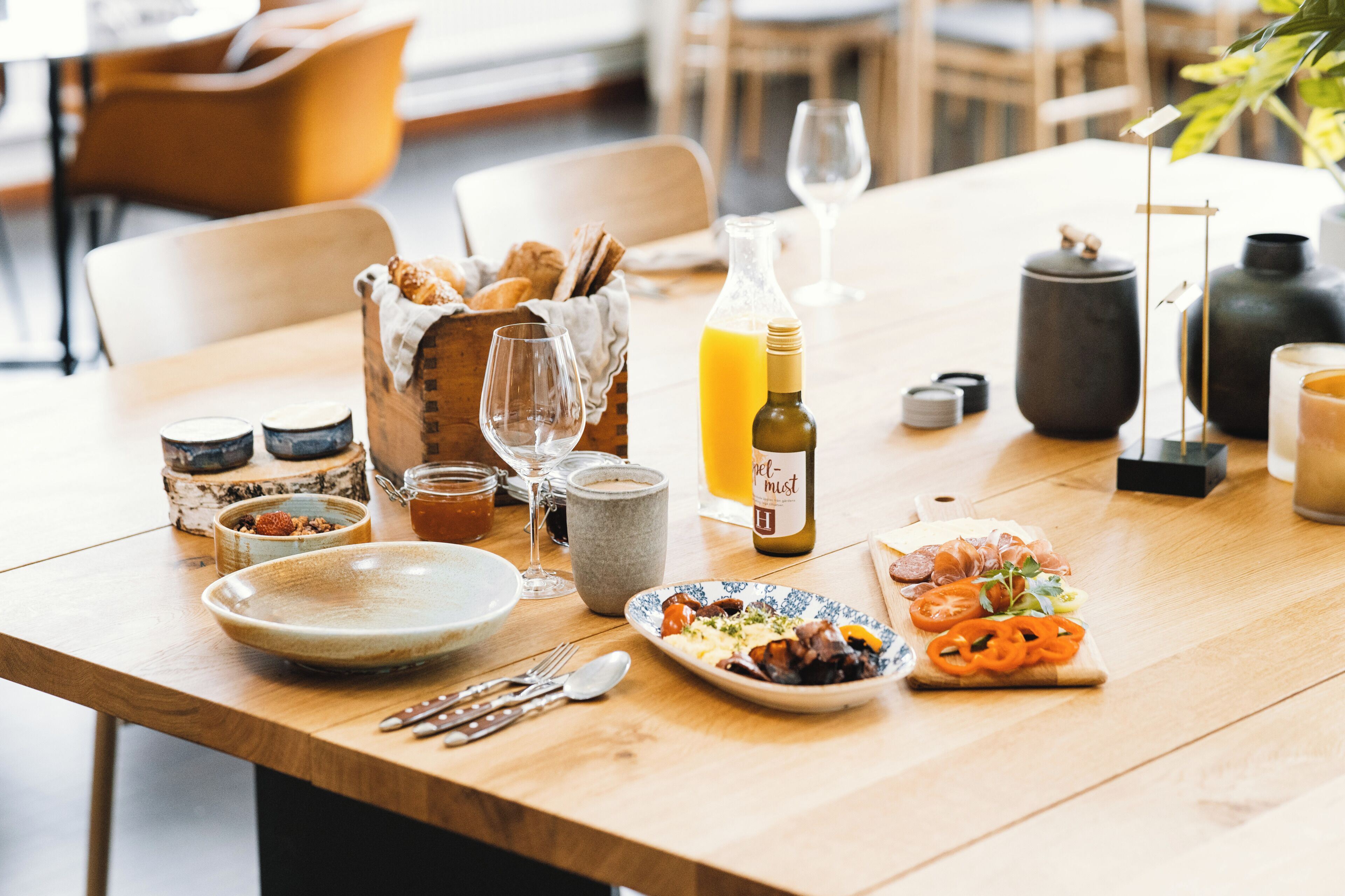 A dining table with a variety of food items, a bottle of olive oil, and several glasses.