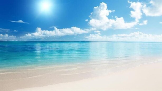 A beach with clear turquoise water and a sandy shore under a bright blue sky with scattered clouds. - Babis Studios (Zakynthos)