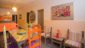 A dining area with a glass table, orange chairs, and a striped armchair. - Babis Studios (Zakynthos)