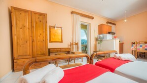 A hotel room with two beds, wooden furniture, a small kitchenette, and a view of the outdoors. - Babis Studios (Zakynthos)