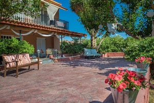 Un patio con un banco de madera, una mesa y plantas en macetas.