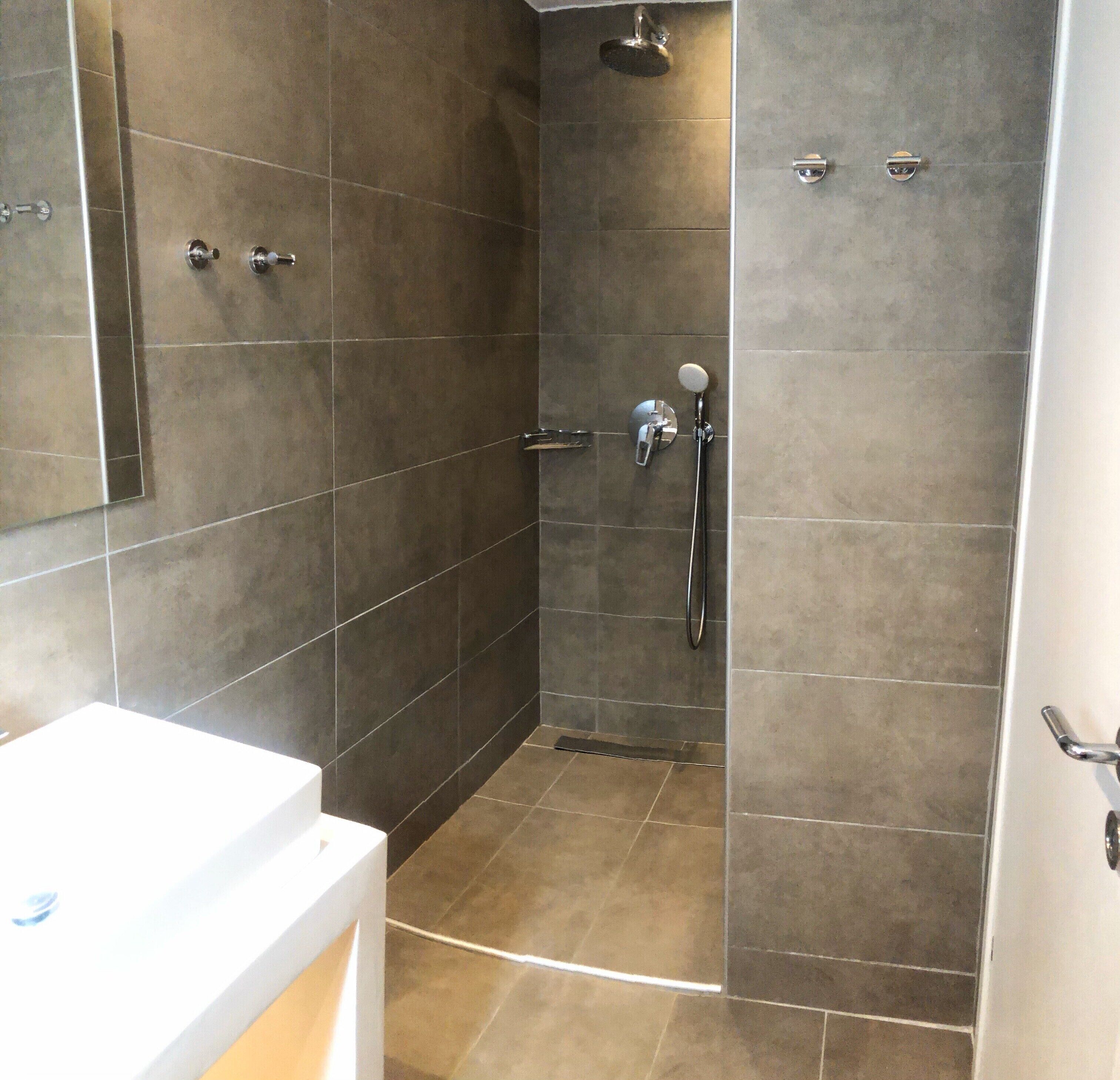 Un baño con ducha, lavamanos y espejo.