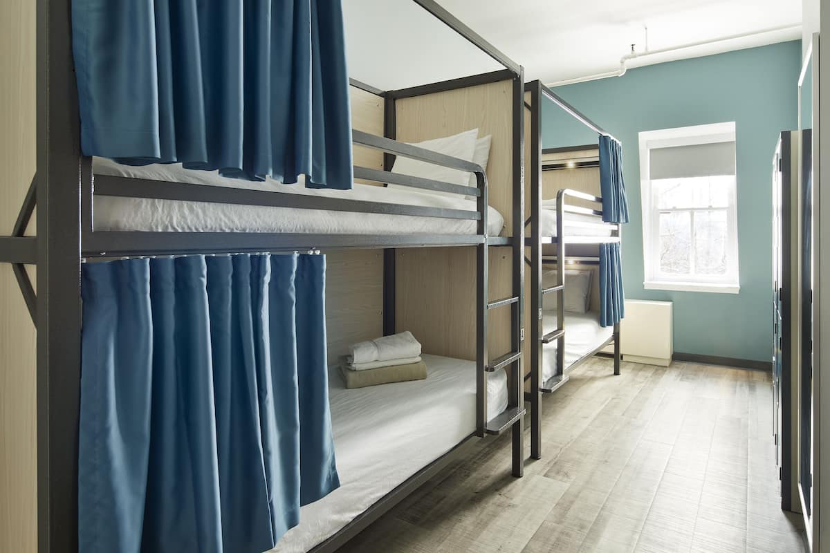 A bunk bed room with blue curtains, a window, and a radiator.