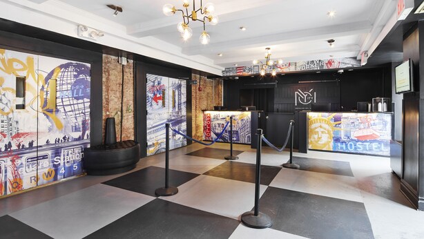 Vestíbulo de hotel con mostrador de recepción, un candelabro y una pared con arte callejero.