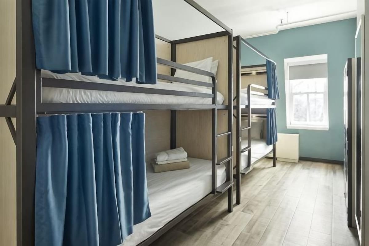 A bunk bed room with curtains, a window, and a radiator.