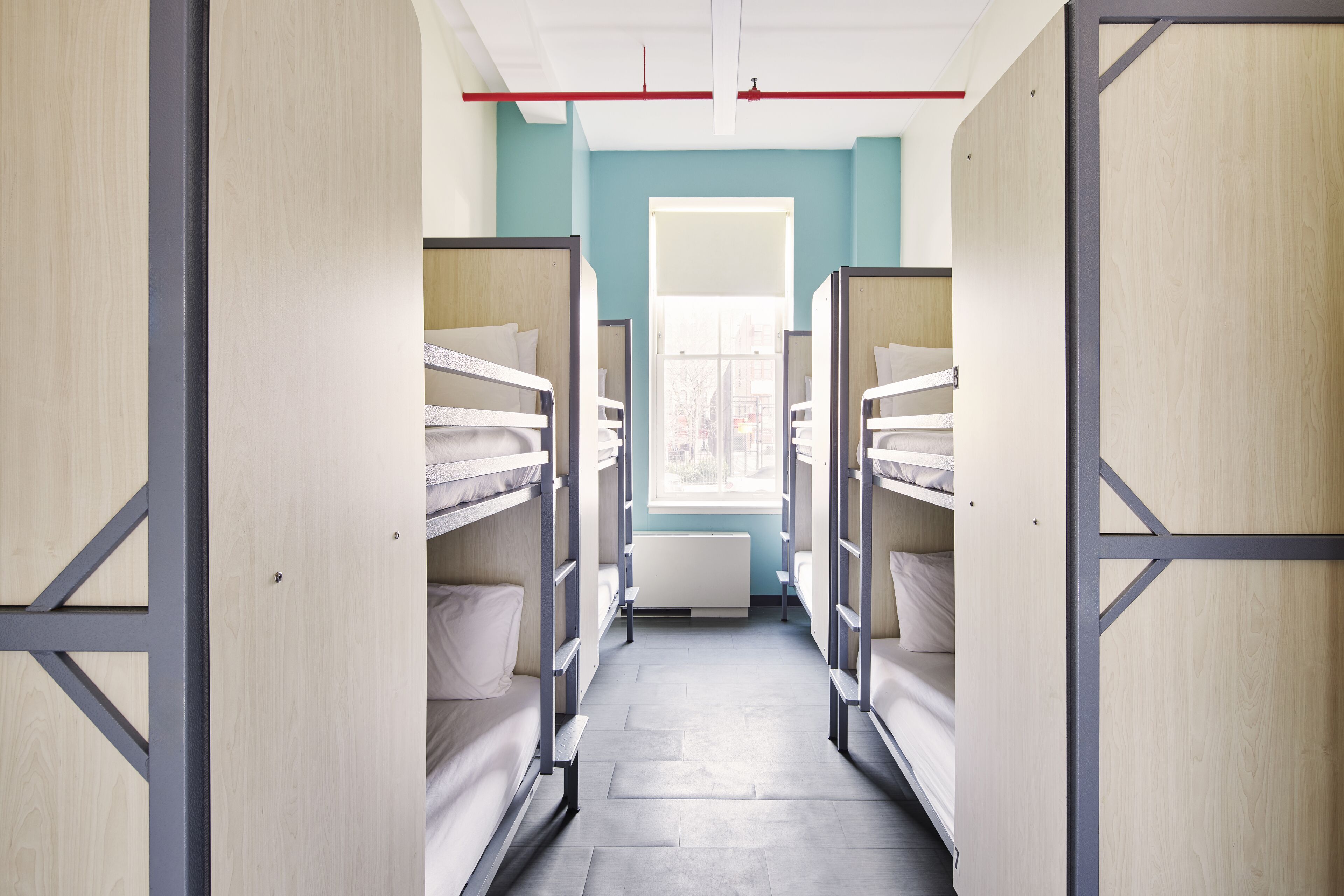 Un couloir avec des lits superposés dans une chambre d’auberge de jeunesse.