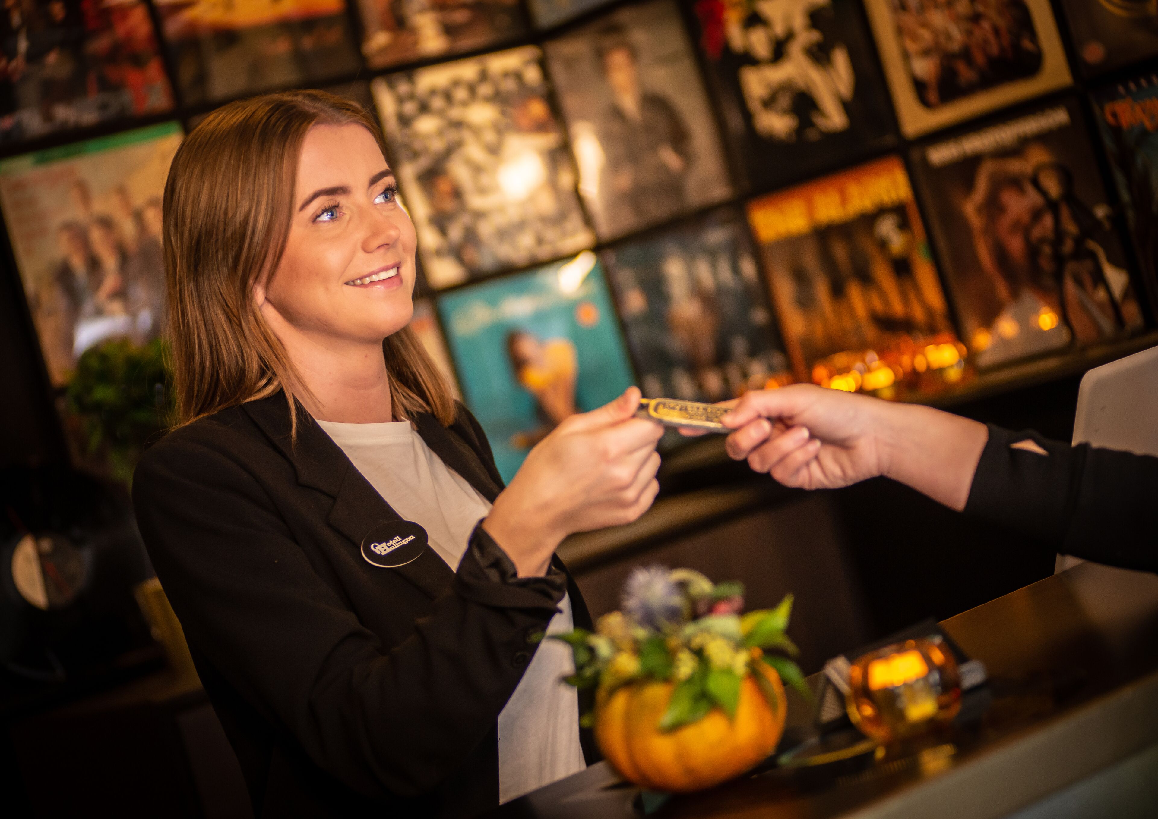 A person receiving a card from another individual at a counter with a decorative pumpkin and candles.