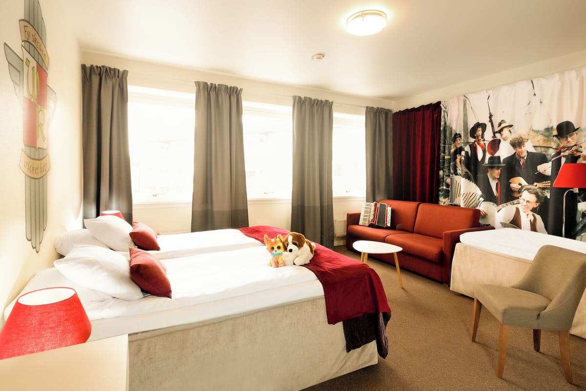 A hotel room with two beds, a sofa, a small table, and a chair.
