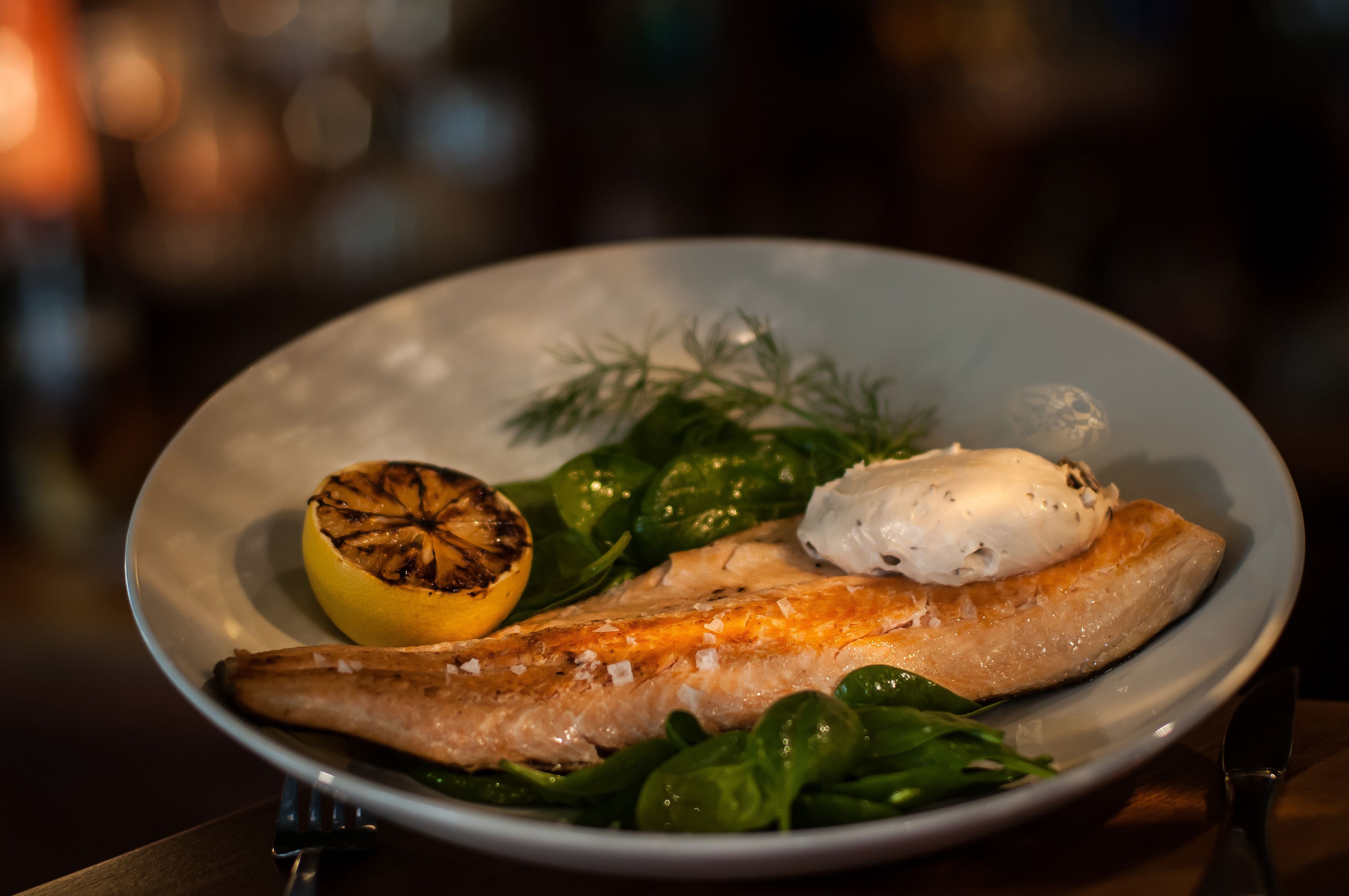 Een bord eten met gegrilde citroen, zalm en spinazie.