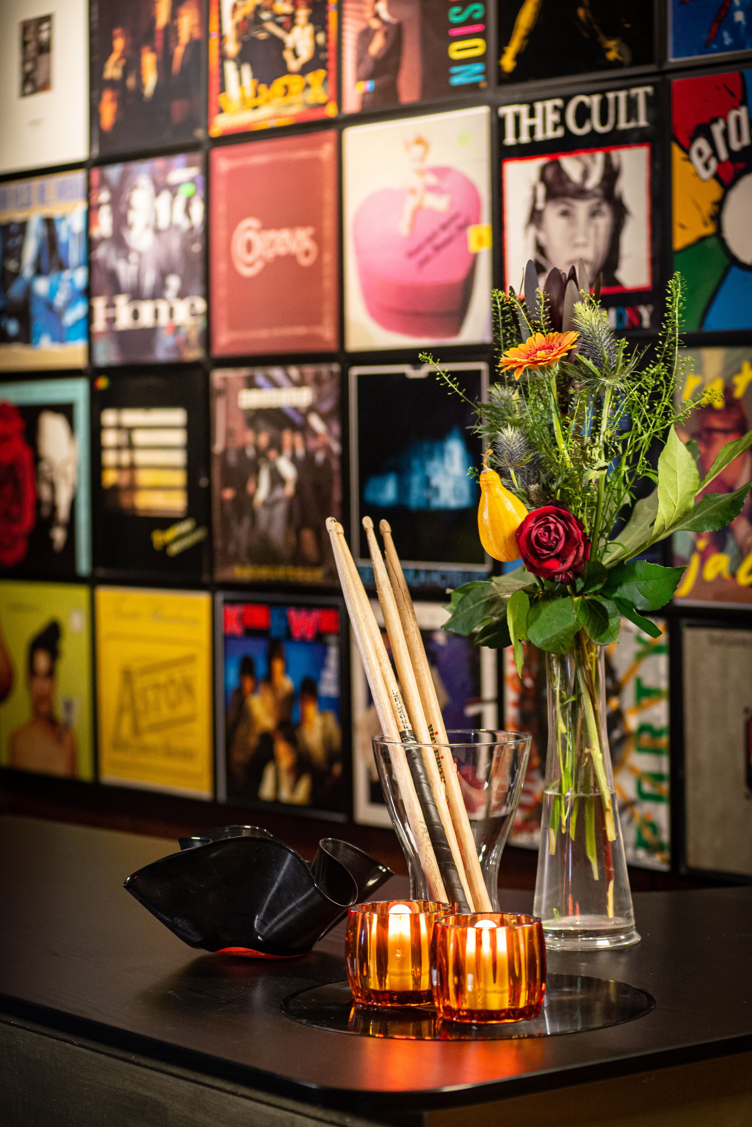 A bar area with a glass vase of flowers, a black cocktail shaker, and a candle holder.
