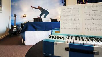 Een kamer met een bed, een gitaar, een keyboard en bladmuziek op een standaard.