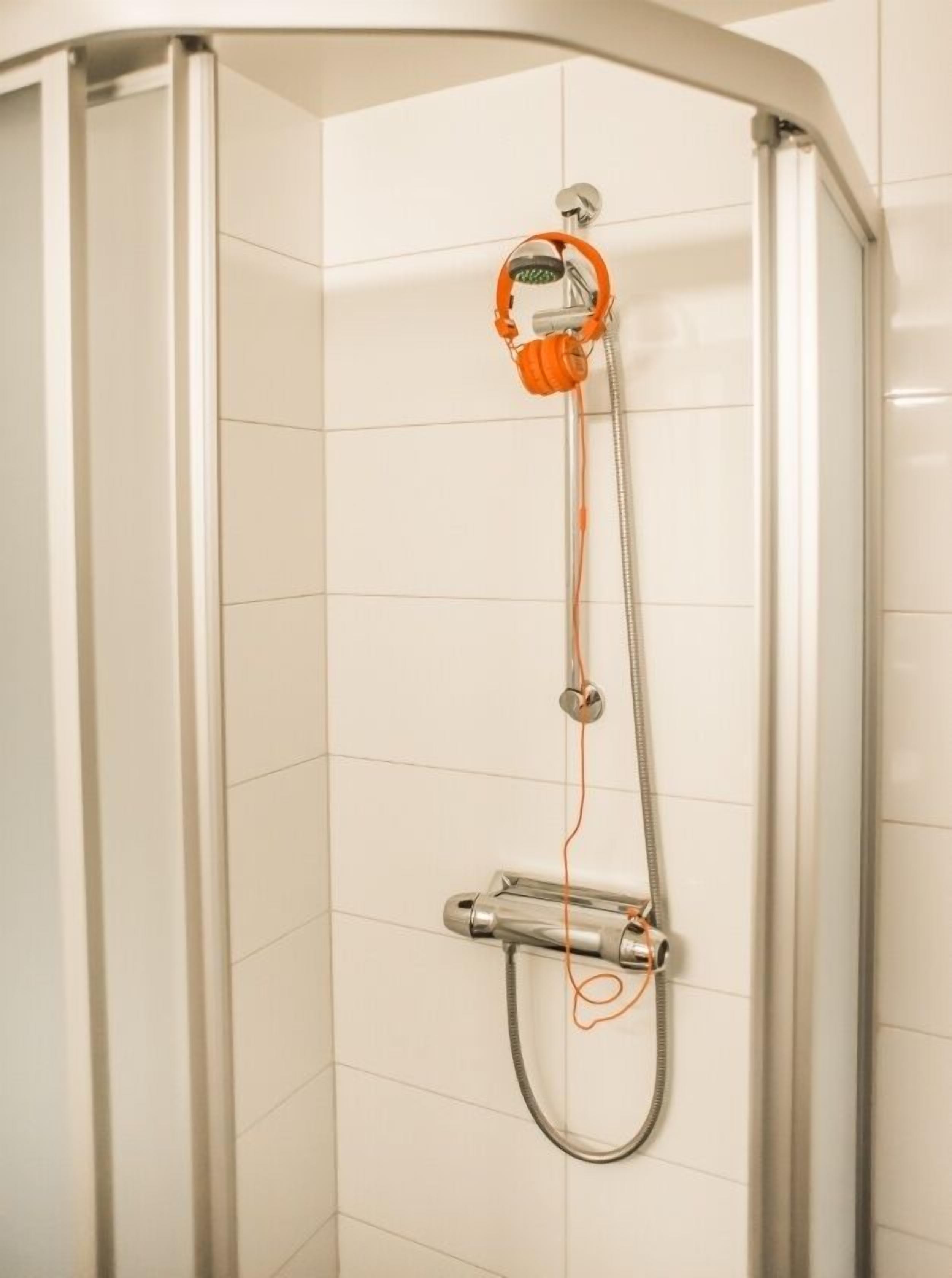 A modern shower enclosure with a handheld showerhead and a handheld faucet.