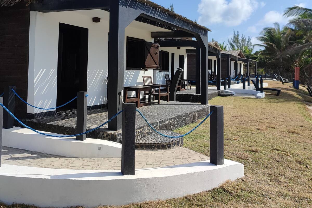 A resort with thatched-roof structures, outdoor seating, and a clear blue sky.