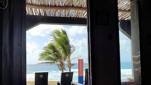 An open doorway leading to a beach with a palm tree and a sign reading "RIBERO DE VILLA". - Riake Resort & Villa (Nosy Boraha)