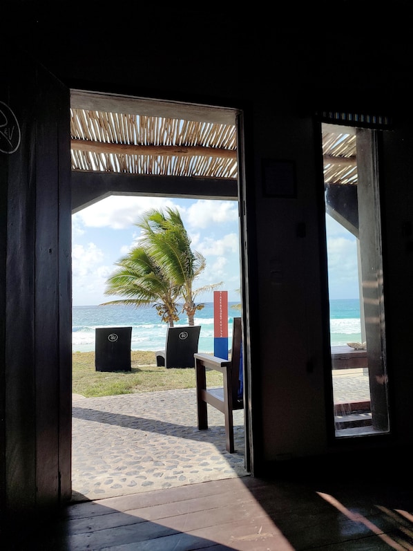 An open doorway leading to a beach with a palm tree and a sign reading "RIBERO DE VILLA".