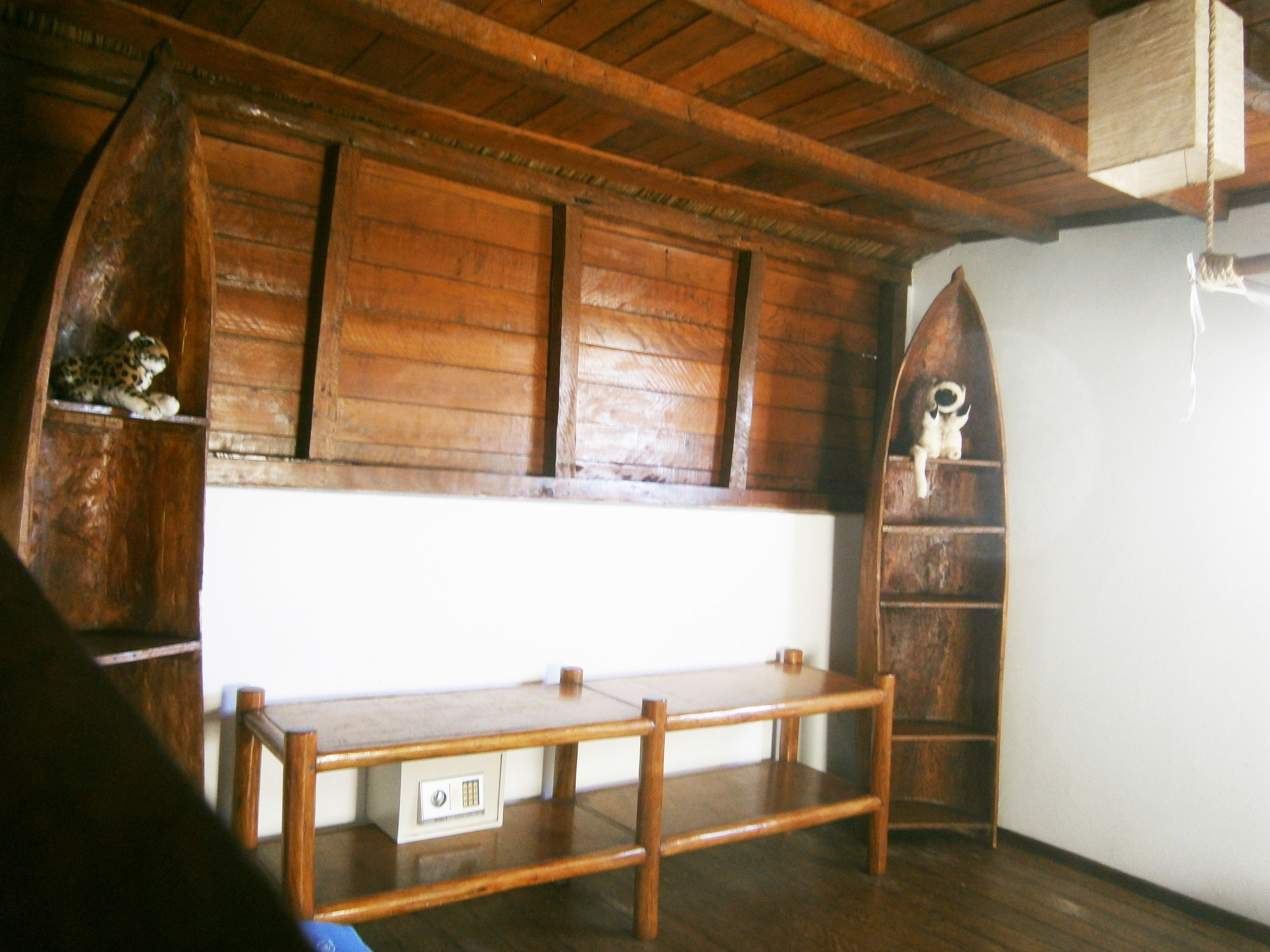 A wooden interior with a bench, a small table, and a shelf with a skull decoration.