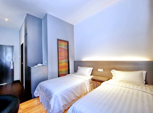 A hotel room with two beds, a large abstract artwork on the wall, a wooden floor, and a modern design.