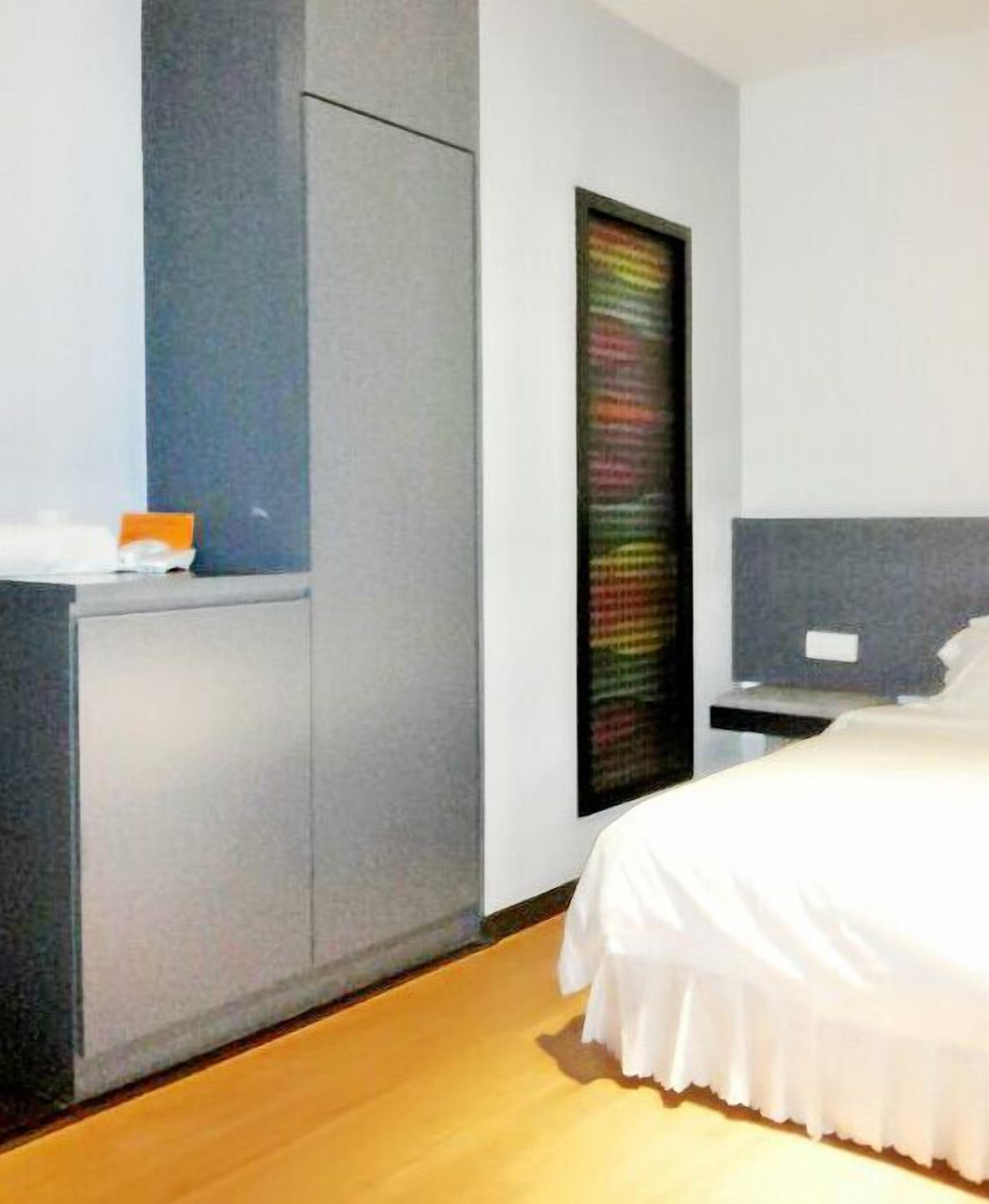 Ein modernes Schlafzimmer mit Bett, Nachttisch, Kommode und an der Wand montiertem Fernseher.