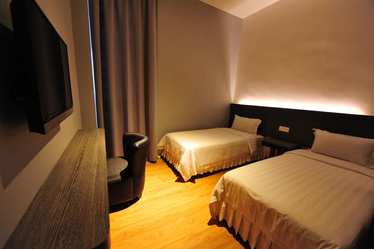 Habitación de hotel con dos camas, un banco, un televisor y una cortina.