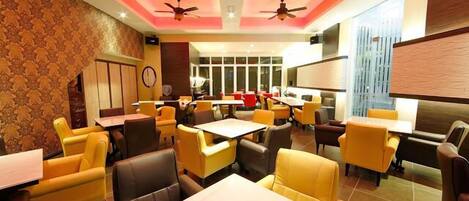 A restaurant with yellow and brown chairs, tables, and ceiling fans.
