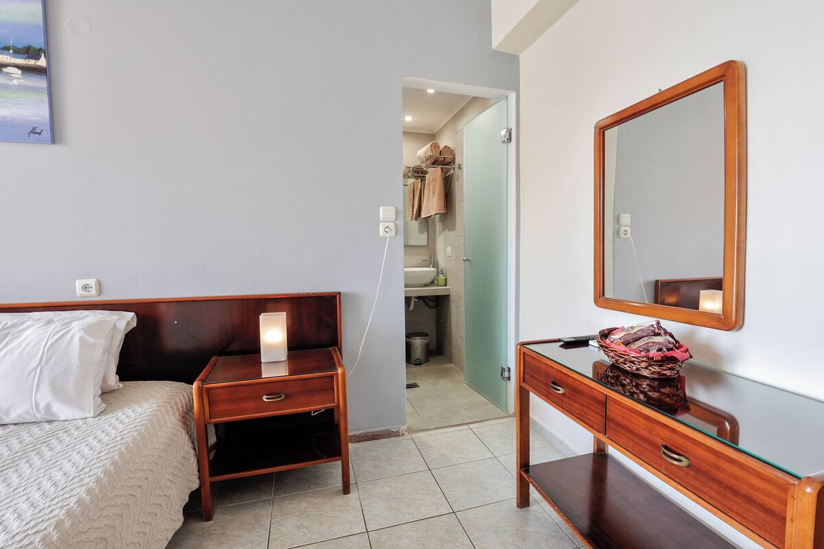 A bedroom with a bed, bedside table, dresser, and a mirror.