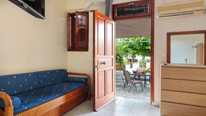 Una habitación con sofá y aparador de madera, y suelo de baldosas.