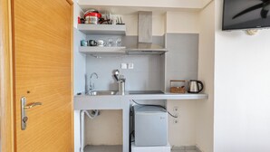 Cocina compacta con refrigerador integrado, un lavamanos y una estufa.