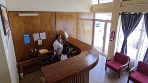 Un área de recepción con un mostrador de madera, un escritorio y dos sillas rojas.