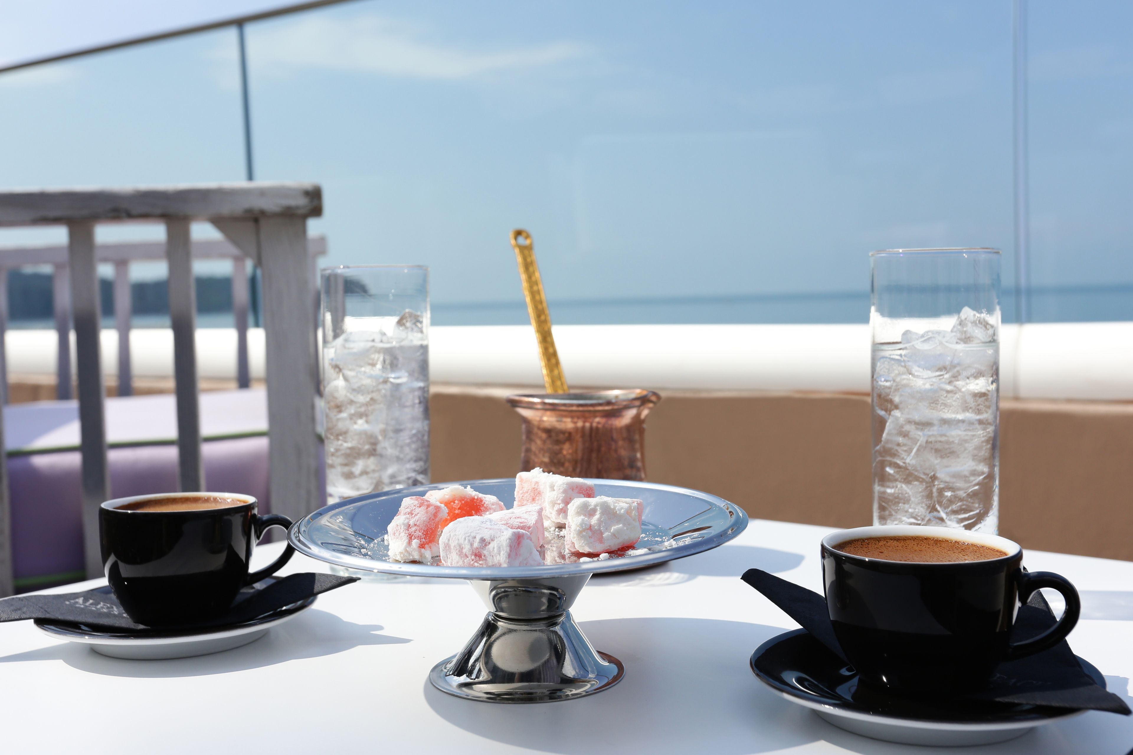 A table with a coffee cup, a glass of water, and a plate of Turkish delight.