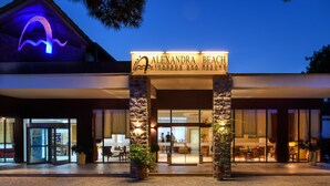 Esterno dell'Alexandra Beach Thassos Spa Resort con un ingresso ben visibile, colonne in pietra e vista diretta sugli interni attraverso le porte vetrate.