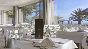 Un ristorante con tavoli apparecchiati per mangiare, una lista dei vini e vista sul mare.