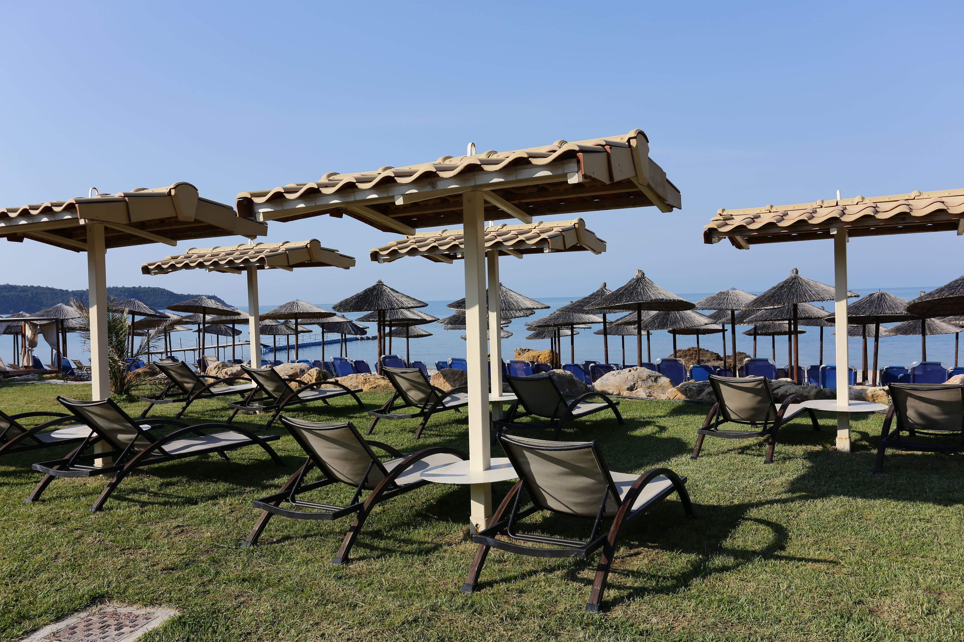 Espace extérieur aménagé avec des parasols et des chaises, situé près d’une piscine.