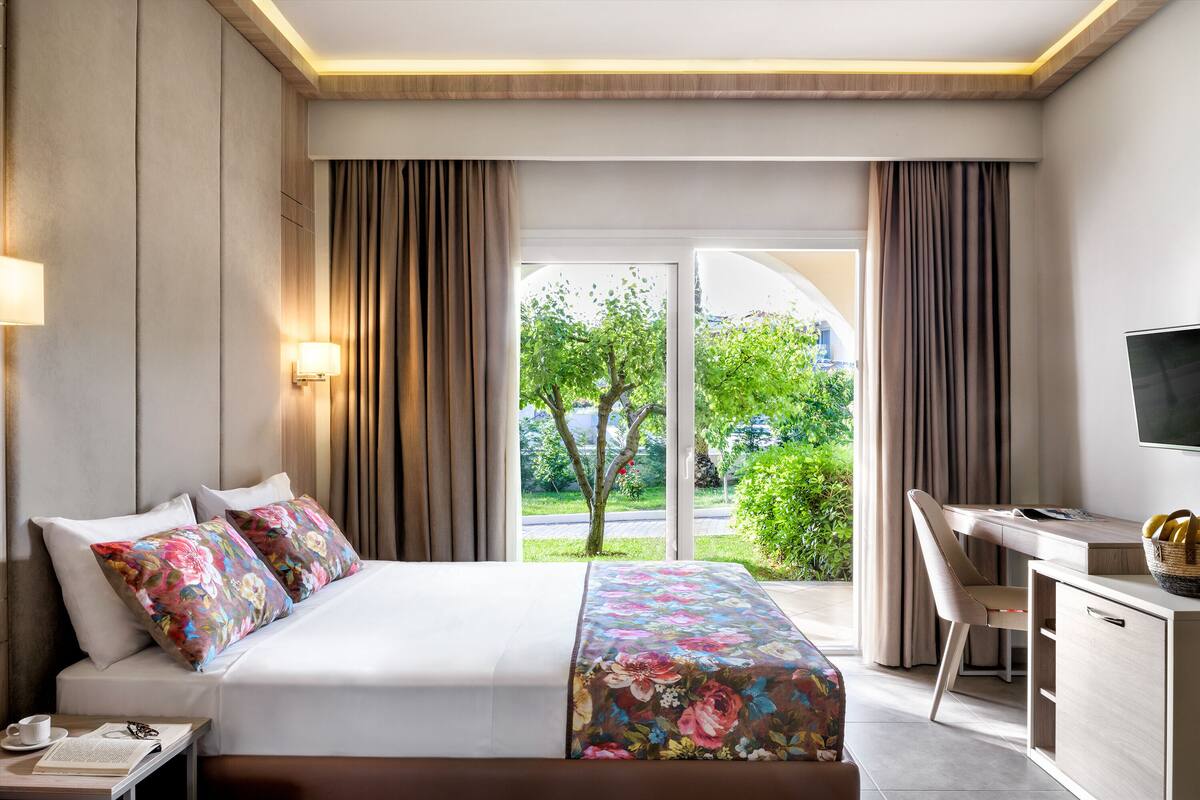 A hotel room with a bed, a desk, and a TV.