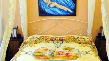 A bed with a floral bedspread, a painting above it, and a canopy.