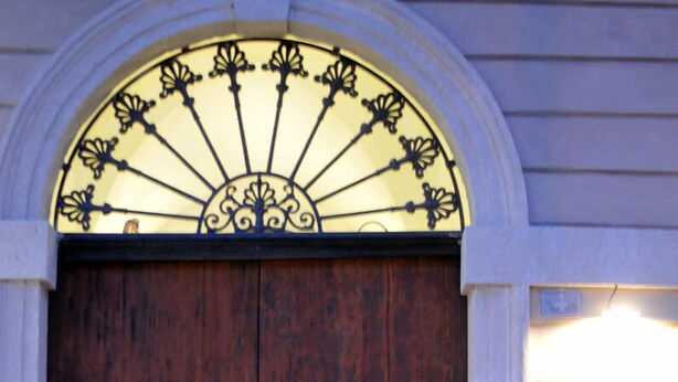 Una puerta doble de madera con un arco metálico decorativo en la parte superior.