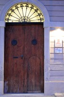 A wooden double door with a decorative metal arch above it.