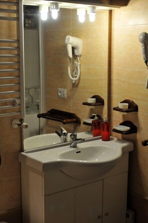 A bathroom with a sink, mirror, towel rack, and a hairdryer mounted on the wall. - Palazzo Osanna (Nardò)