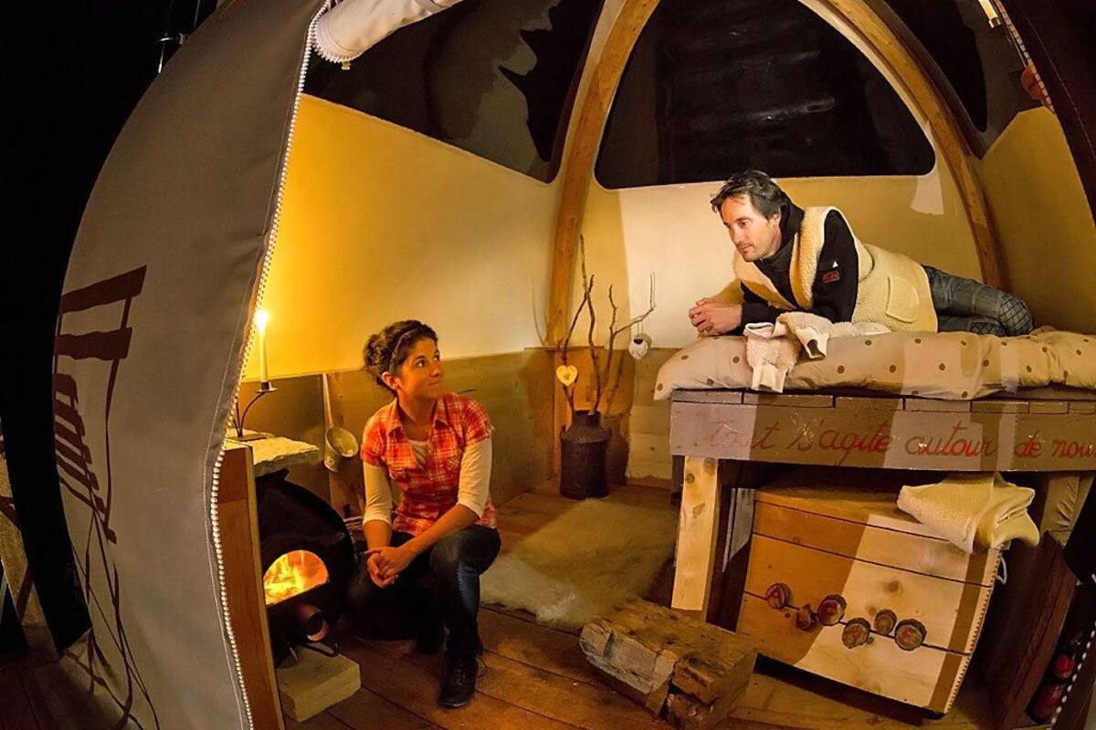 Un espacio acogedor de estilo rústico, tipo tienda, con chimenea, muebles de madera y una zona de descanso.