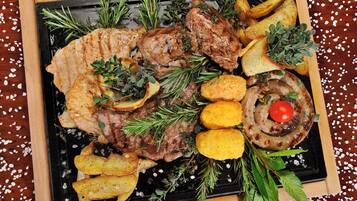 Lombo de porco assado com batatas e alecrim sobre um prato de ardósia preta.