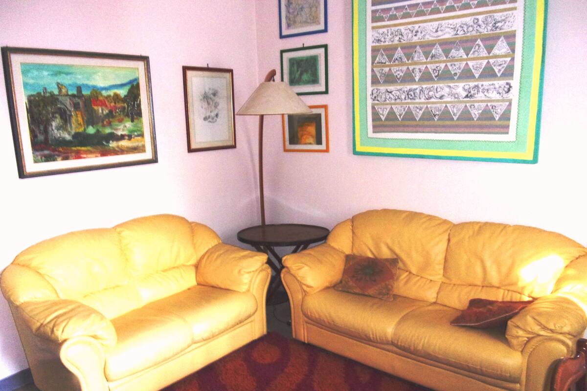 A room with two yellow leather sofas, a small round table, and a lamp.